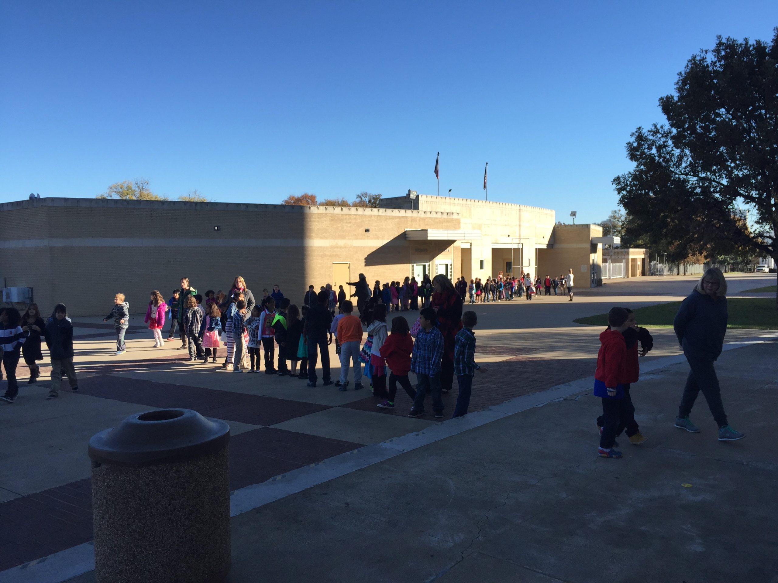 Elementary students lining up outside school building on sunny day
