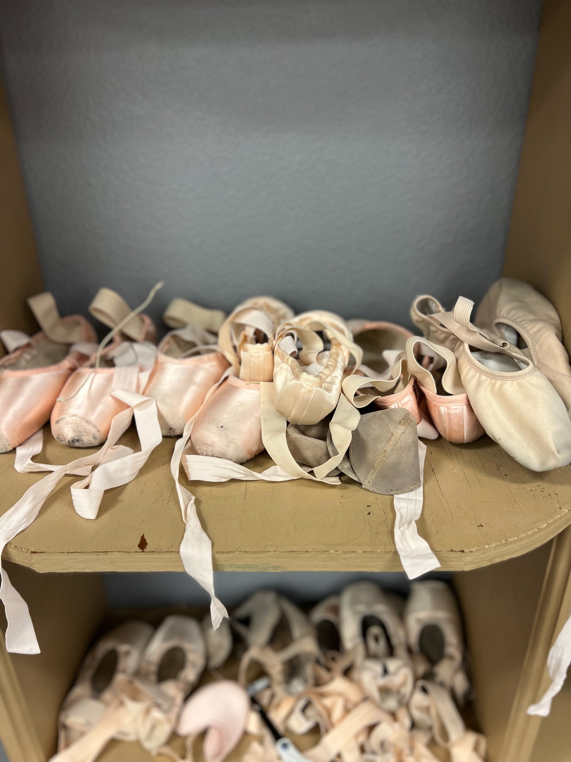 Worn pointe shoes resting on stage floor, reflecting the strength, dedication, and artistry built through years of training at North Central Ballet
